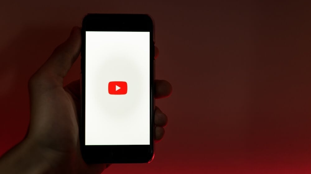 youtube load screen on cell phone held in hand with red background