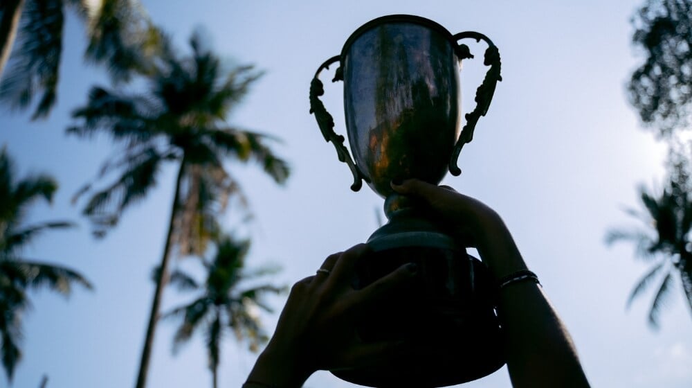 Person holding a sports trophy up to the sky