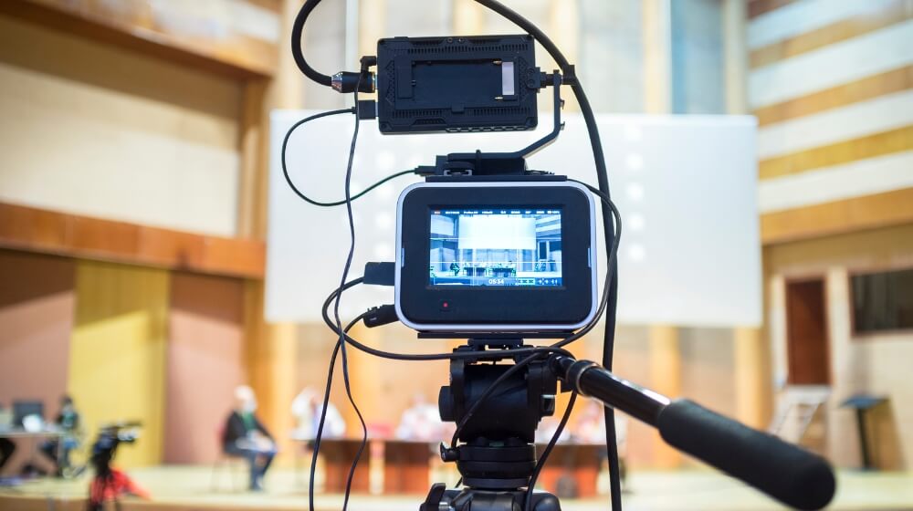 camera set up to film an event blurred in the background